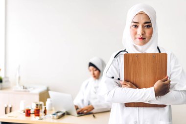 Profesyonel tıp. Steteskoplu, üniformalı, hastane masasında dizüstü bilgisayarla çalışan iki Müslüman kadın doktor. Sağlık ve tıp.