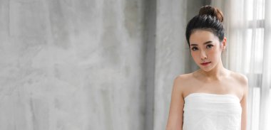 Gülümseyen, güzel, güzel Asyalı bir kadının portresi. Beyaz giysiler içinde taze, sağlıklı beyaz bir ten. Düşen ve pankartta eğlenen bir kız.