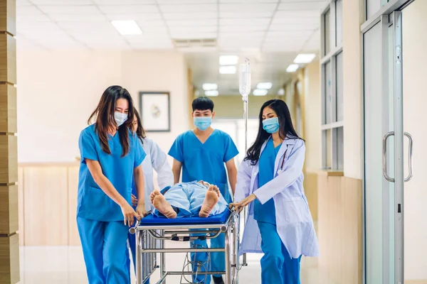 Group of professional medical doctor team and assistant with stethoscope in uniform taking seriously injured patient to operation emergency theatre room in hospital.health medical care concept