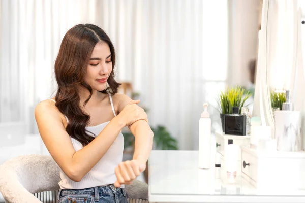 Smiling of young beautiful pretty asian woman clean fresh healthy white skin looking at mirror.Asian beauty girl touching on her hand and applying cream at home.spa and beauty concept