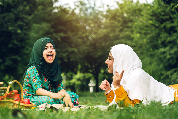 Portrait of happy religious enjoy happy love asian family arabic muslim mother and little muslim girls child with hijab dress smiling and having fun moments good time in summer park