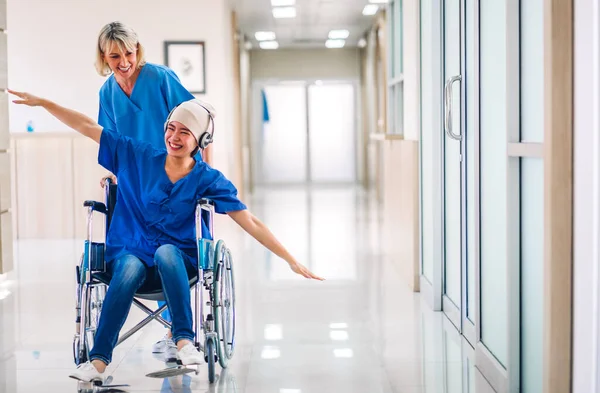 Professional medical doctor with stethoscope in uniform discussing and dancing with happy patient woman with cancer cover head with headscarf of chemotherapy cancer in hospital.health care