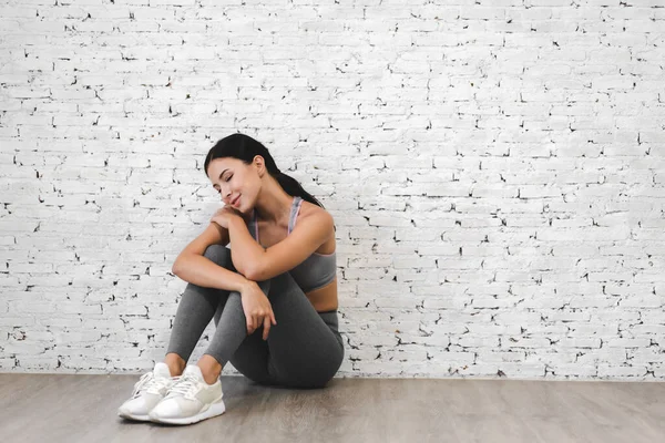 运动女性穿着运动服 在运动后放松地坐着 与有白墙背景的文字相映成趣 健身和健康的生活方式 — 图库照片