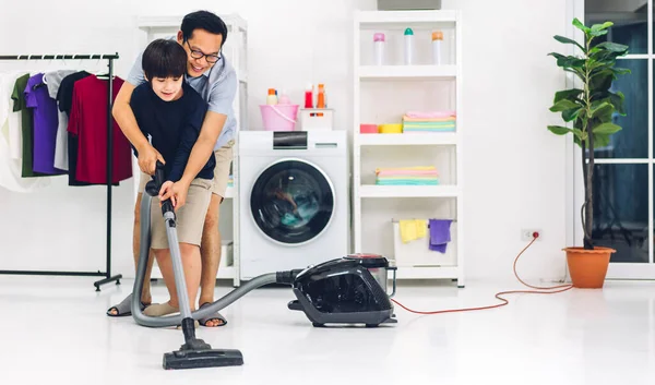 爸爸教亚洲小孩的小男孩玩的开心 做家务活 打扫地板 用吸尘器擦拭灰尘 同时在家里一起打扫房子 — 图库照片
