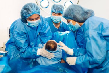 Profesyonel anestezi uzmanı doktor tıbbi ekip ve asistan bebek sezaryeni yapıyor ve bebeği modern hastane ameliyathanesinde doğum ekipmanıyla doğuruyor.
