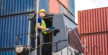 Miğferli profesyonel mühendis konteynır ustabaşı ayakta çalışıyor ve telsiz kullanıyor stokları yükleme için konteynıra koyuyor. Lojistik ve iş ihracatı