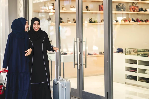 Two young friend beauty islamic asian arabic muslim woman wearing a hijab enjoying shopping and having fun talking together look in the shop window outdoors at fashion store