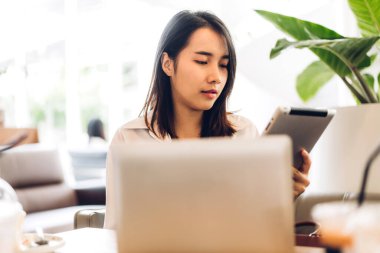 Gülümseyen mutlu Asyalı bir kadının portresi dizüstü bilgisayar teknolojisini kullanarak rahatlıyor. Genç hippi Asyalı kız serbest çalışıyor ve kafeteryada yeni fikirler üretiyor.