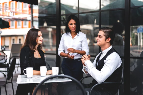 Bir grup neşeli genç arkadaş buluşmayı tartışıyor ve birlikte kahve içerek eğleniyorlar. Kafe masasında ve restoranda karışık ırkçı insanlar oturuyor.