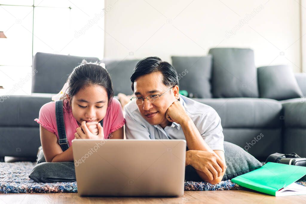 Father and asian kid little girl learning and looking at laptop computer making homework studying knowledge with online education e-learning system.children video conference with teacher tutor