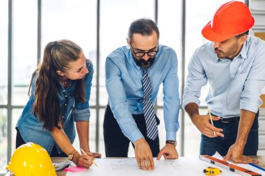 İnşaat sahasında planlar ve inşaat araçlarıyla çalışan miğferli ekip mühendisi ustabaşı.