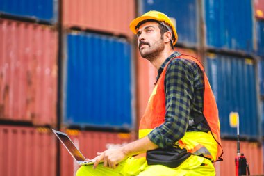 Kasklı profesyonel mühendis konteynır ustabaşı ayakta çalışıyor ve telsiz kullanıyor. Stokları yükleme için konteynıra koyuyor. Lojistik ulaşım ve iş sektörü ihracatı