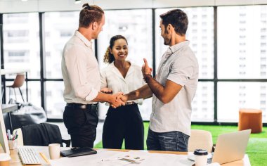 Zarif takım elbiseli iki iş ortağı modern ofiste başarılı bir şekilde tokalaştılar. Ortaklık onayı ve jest konsepti için teşekkürler.