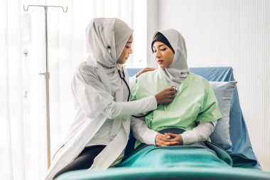 Müslüman Asyalı kadın doktor hizmetleri, steteskop muayenesi yapan Müslüman kadın hastaları muayene etmek ve hastanede sağlık hizmetleri konseptiyle ilgili bilgileri kontrol etmek için destek vermektedir.