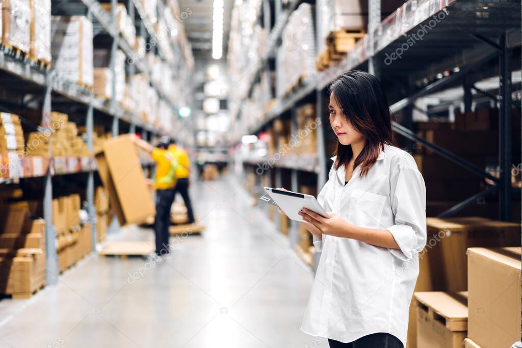 Portrait of asian woman standing and order details on tablet for checking goods and supplies on shelves store at factory with goods background in distribution industry warehouse.logistic and business export