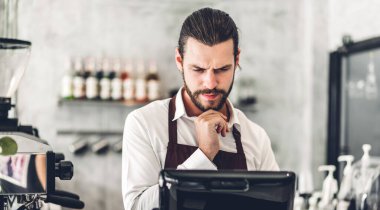 Yakışıklı sakallı baristanın portresi. Küçük işletme sahibi. Kafenin arkasında bilgisayarla çalışıyor.