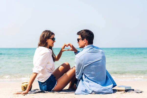 这对年轻夫妇喝椰子汁 阅读一本关于热带海滩的书 夫妇在海滩上放松一下 — 图库照片