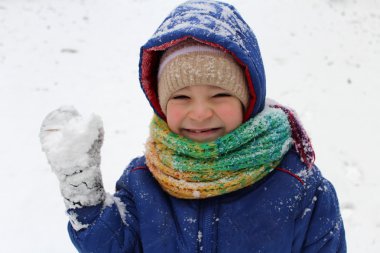 Küçük çocuk kışın karla oynuyor..