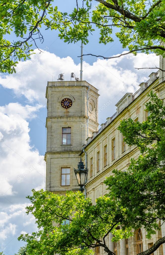 The clock tower of the old Palace in Gatchina Park on a background of blue sky and clouds
