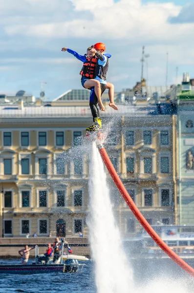 Atleta senza volo con una ragazza a portata di mano contro il cielo blu, nuvole e palazzi sul lungomare di San Pietroburgo . — Foto Stock