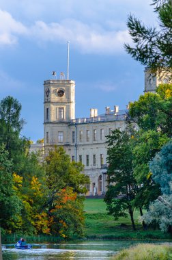 Gatchina Palace Park mavi gökyüzü ve bulutlar karşı gölün kıyısında antik bir sarayda.