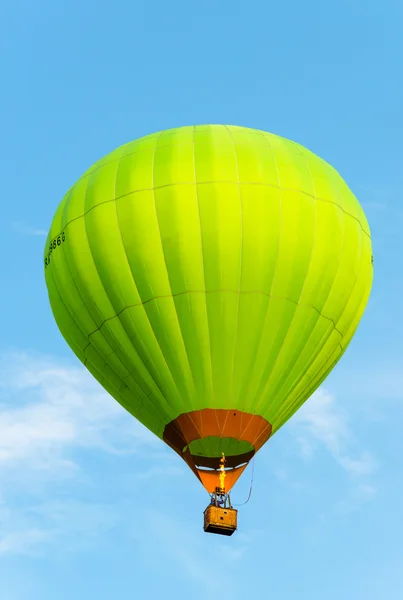 Balão de ar quente verde em voo contra o céu azul . — Fotografia de Stock