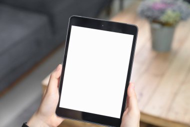 Oturma odasındaki kanepede siyah tableti tutarken yakın plan..