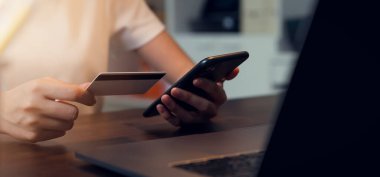 Akıllı telefon kullanan ve cep telefonuyla ödeme yapan bir kadın..