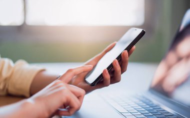 Akıllı telefon tutan ve sosyal ağdaki arkadaşlarıyla sohbet eden genç bir kadının yakın çekimi..