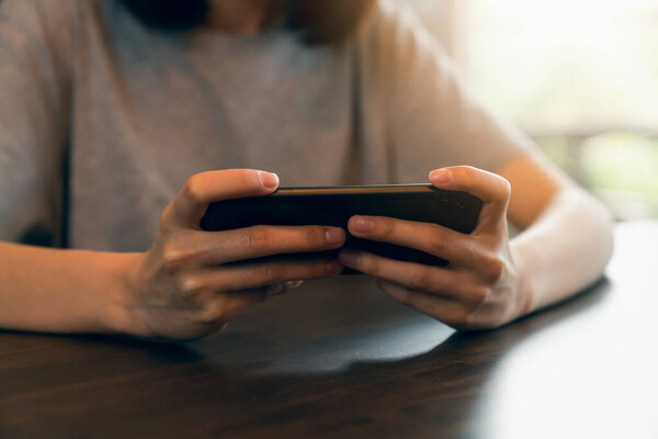 Крупный план молодой женщины, держащей в руках смартфон и общающейся с друзьями в социальной сети.