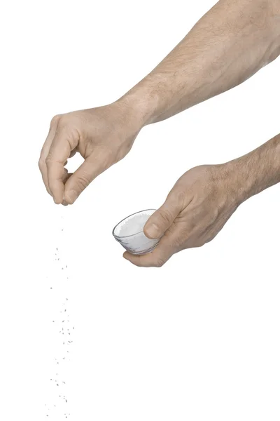 Tw manos masculinas añadiendo sal triturada sobre un fondo blanco Fotos De Stock
