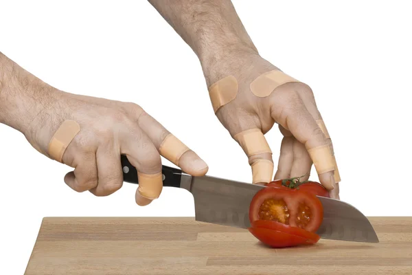 Manos lesionadas con cuchillo cortando un tomate Imágenes De Stock Sin Royalties Gratis