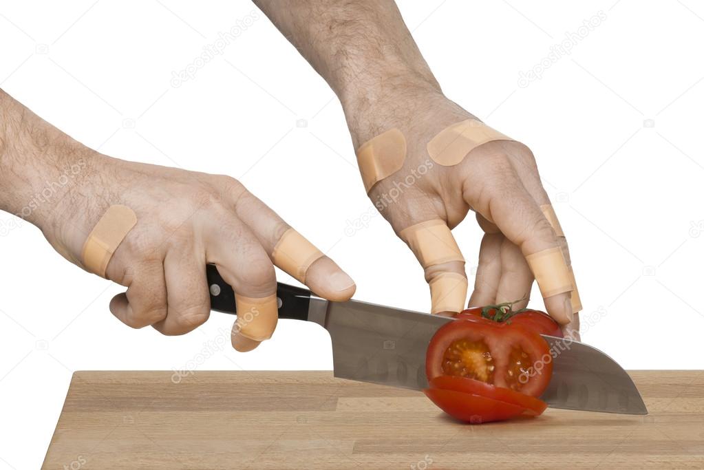 Injured hands with knife cutting a tomato