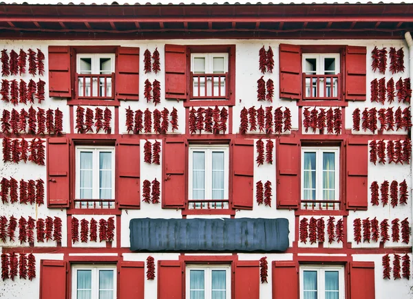 Pimientos Espelette rojos secándose en la pared de la casa vasca — Foto de Stock