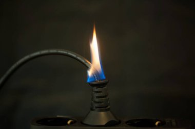 Fiş soketi alev ve koyu arkaplan ile yakılıyor. 