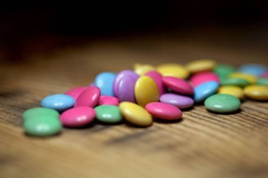 Koyu ahşap arka planda farklı renkte şekerler.