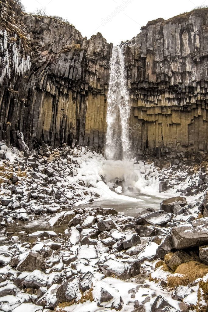 Svartifoss waterfall in the gorge, winter trail, travel in Iceland. High quality photo