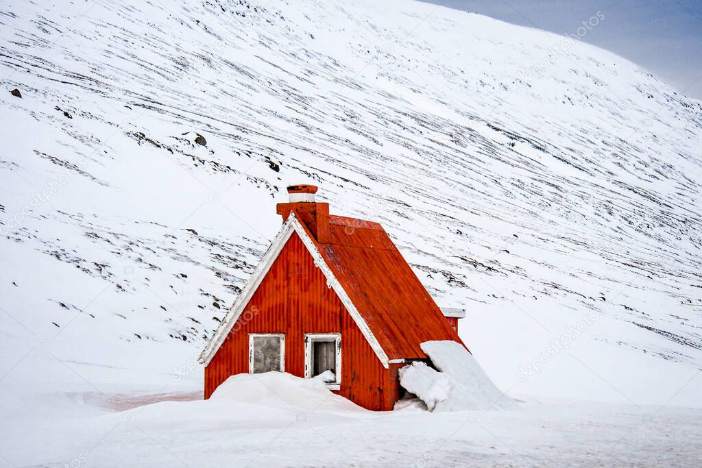 Alone snow covered house in Iceland mountains