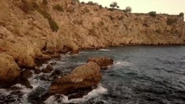 Bir adam Antalya 'nın kayalık sahillerinde balık tutuyor.