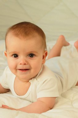 Mutlu bir çocuk karnının üstünde yatıyor. Ellerini uzattı..