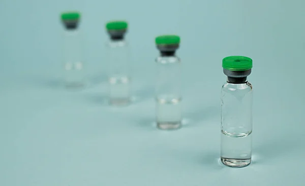 glass jars with a green lid for medicines are placed one after the other. medical jar for the drug. for chemical liquid substances.
