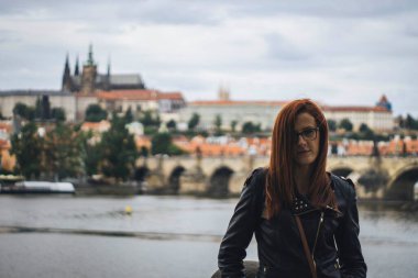 Prag 'da kalenin önünde poz veren genç bir kadın.