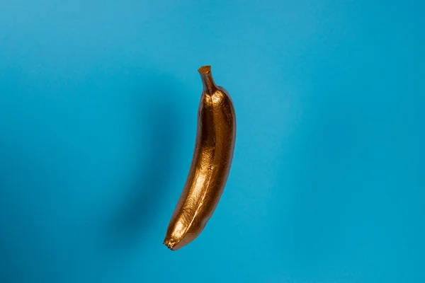 Guld Flytande Banan Blå Bakgrund Minimalt Livsmedelskoncept — Stockfoto