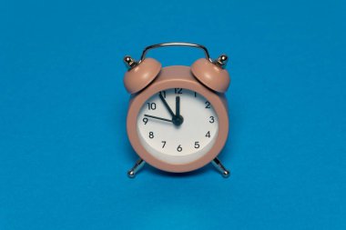 Mavi arka planda kahverengi alarm retro saati. 12 'ye beş var. Yaratıcı zaman kavramı