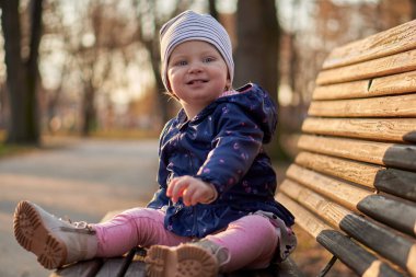 Parktaki bankta gün batımında küçük bir kız bebek. Mutlu kız. Kış zamanı