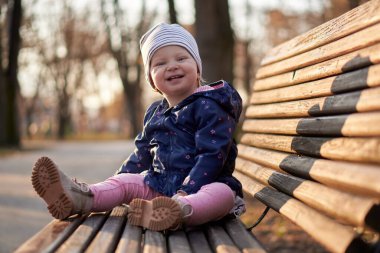 Parktaki bankta gün batımında küçük bir kız bebek. Mutlu kız. Kış zamanı                               