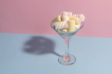 Martini bardağında renkli marşmelovlar. Pastel mavi ve pembe renkler