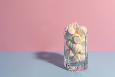 Gölgeli bir bardakta renkli şekerlemeler. Pastel mavi ve pembe renkler. Üst görünüm