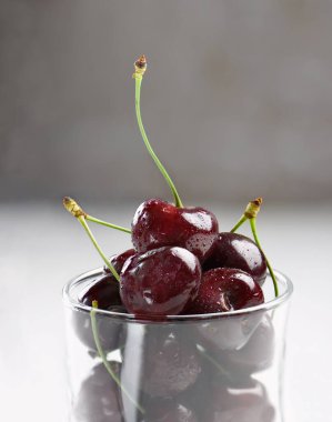 Kapalı kırmızı kirazlar, bardakta su damlaları.. 