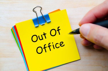 Out Of Office text on stack of multicolored notepads